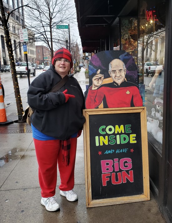 Anne outside in the cold, pointing an outdoor chalkboard reading "Come inside and have Big Fun". Atop the sign, a hand-drawn Captain Picard is about to make his classic "Engage!" hand signal.