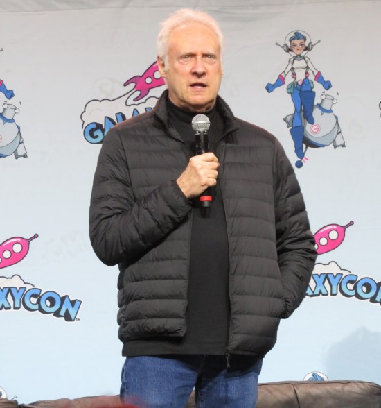 Brent Spiner on stage, talking seriously into his mic.