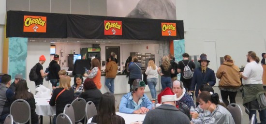A concession stand with three Cheetos signs and a long line.
