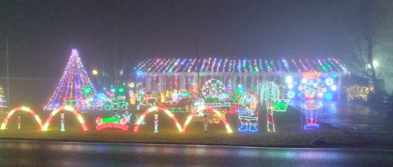 Someone's front yard at night, covered in thousands of Christmas lights.