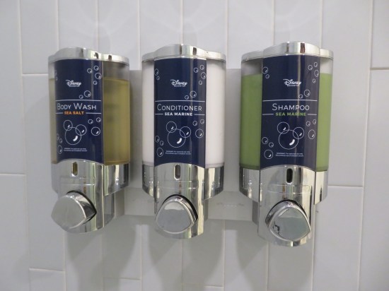 Disney brand dispensers mounted on the shower wall: sea salt body wash, Sea Marine conditioner, and Sea Marine shampoo.