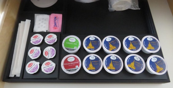 A drawer holding a dozen Disney Keurig cups, creamer, sweeteners and stir sticks.