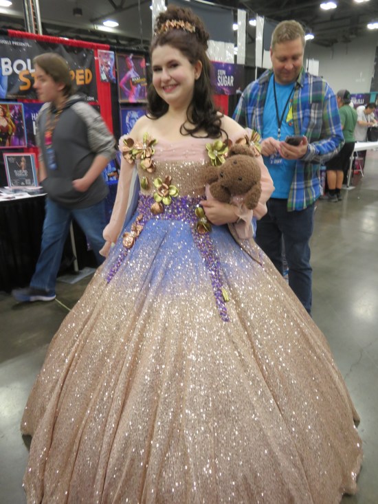 Woman in a blue and pink ballroom dress, holding a stuffed dog.