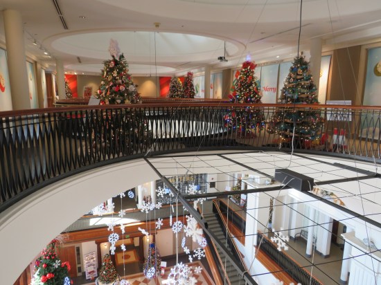 Top floor of a museum with Christmas trees in it. The floor has large openings for viewing the lower levels unless you're acrophobic.