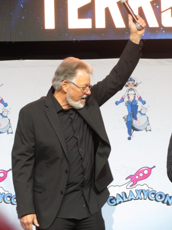 Frakes with arm raised high, mic in hand.