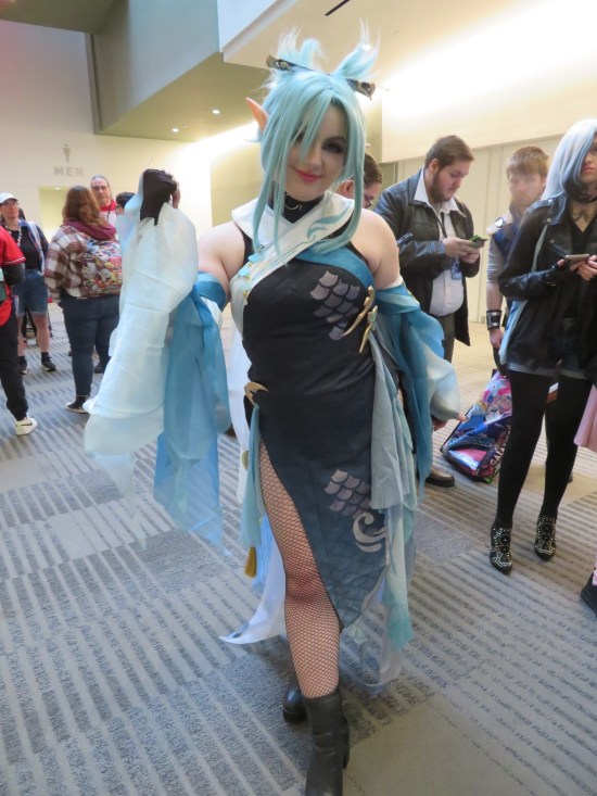 Video game female warrior in black dress, blue trimmings, blue hair, hair clip, and pointed ears.