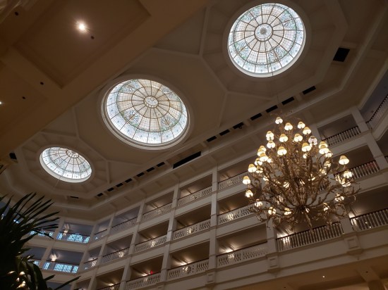 lobby ceiling with three large round skylights and a chandelier, all shot at a weird Dutch angle.
