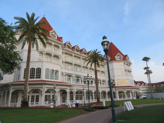 Four-story white Victorian building with red roofs and palm trees.