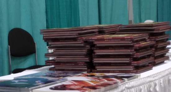 Several stacks of Squickerwonkers books on Evangeline Lilly's autograph table, next to her 8-x-10 photos.