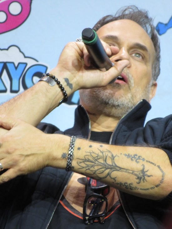 Todd Stashwick with his left forearm bared, revealing a Yggdrasil tattoo with Elvish writing around it.