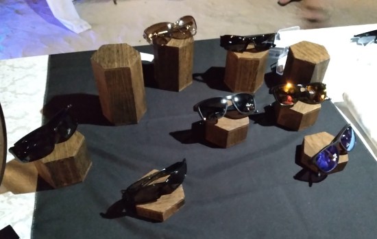 A table with nine wooden bases, seven of them topped with pairs of sunglasses.