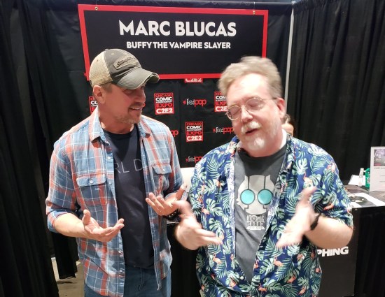 Me chatting with Marc Blucas in front of his autograph table, neither of us looking at the camera. I'm blurry and have my eyes closed.