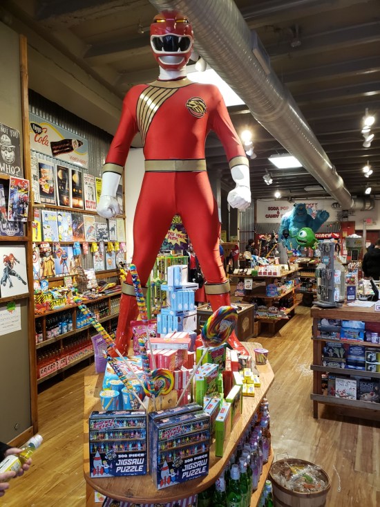 Life-sized Red Power Ranger statue atop a candy store table.