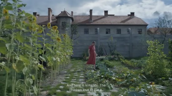 The wife of Auschwitz's commandant shows off her massive garden. At the backyard's edge is the ten-foot stone wall surrounding the concentration camp.