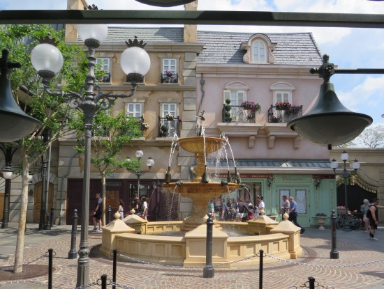Fancy fountain with French-like storefronts behind it. Some are real shops; some are facades.