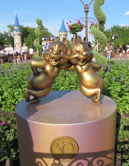 Gilded statues of two chipmunks who are best friends leaning on each other and planning to loot your fridge.