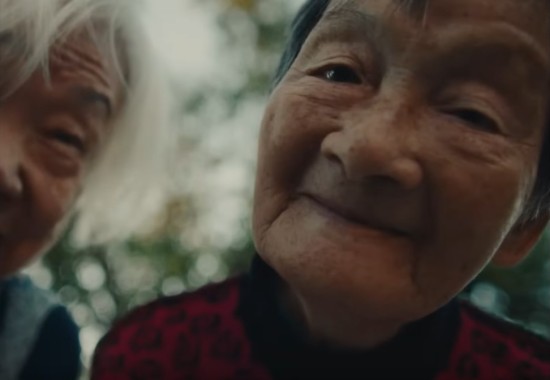 Two Taiwanese grandmas smile into the camera really close up.