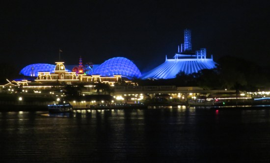Disney World's Tomorrowland section at night, zoomed in from afar, all curved surfaces covered in blue lights.