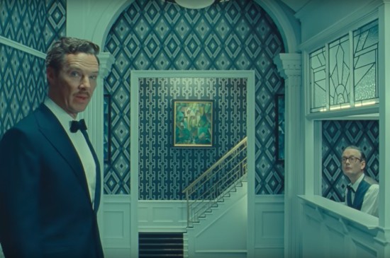 An extremely blue, symmetrically obsessive casino foyer. At left, Benedict Cumberbatch in a blue tux and tiny mustache talks to the viewer. At right, an older gent in large glasses and a vest sits in a clerk's box.