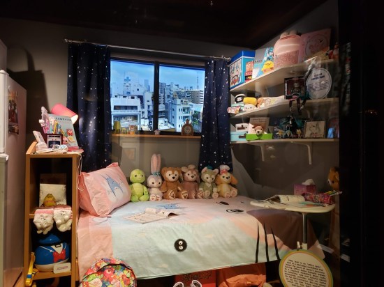 Simulated bedroom. Bed is covered with too many stuffed animals. Shelves are packed with kids' stuff.