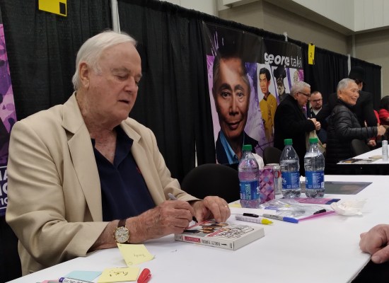 John Cleese signing my Fawlty Towers DVD set. At far right are George Takei at his table along with his husband Brad.
