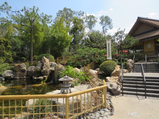 Large koi pond with rocks and lantern in front of Japanese restaurant.