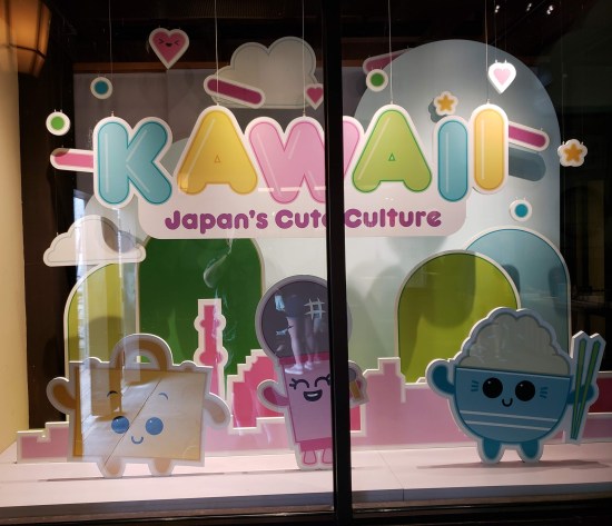 Initial display case for an exhibit called "Kawaii: Japan's Cutre Culture". Three happy kiddie product mascots, hearts and candy are among the decorations.