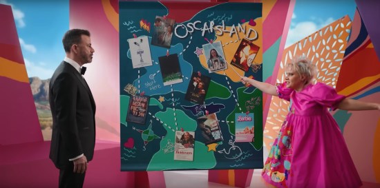 Kate McKinnon's Weird Barbie invites Jimmy Kimmel into her Barbieland house and unrolls a large presentation map of "Oscarsland", which looks like a Candyland game board with photos of each of the ten Best Picture nominees scattered along its dotted-line path.