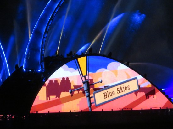 Closeup of archway cartoon that focuses on a sign that says "Blue Skies" in whimsical New York Times Roman font. Fountains above are dark blue.