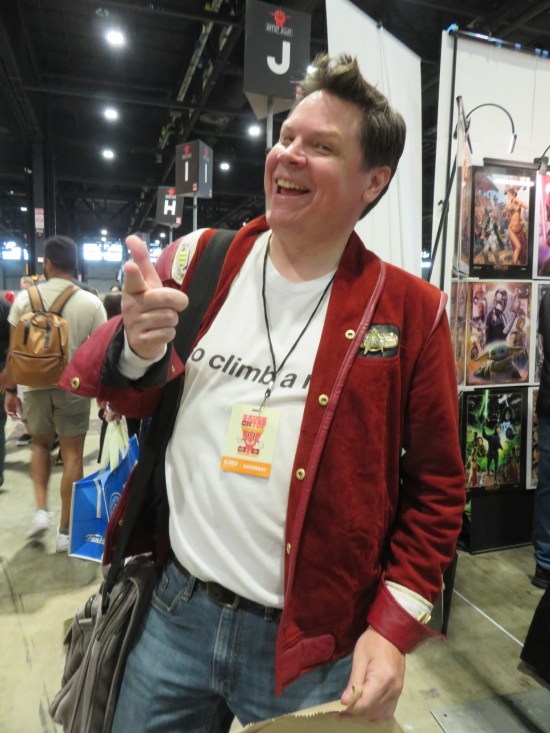 Fan in a red Trek jacket and a T-shirt that says "Go climb a rock."