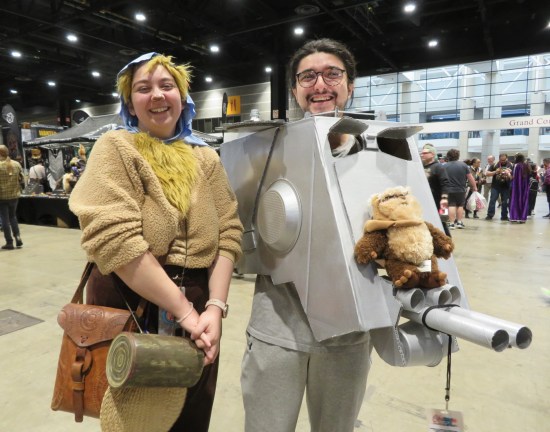 Woman in a n Ewok costume. Guy wearing an AT-ST cockpit that has a stuffed Ewok perched on the front.