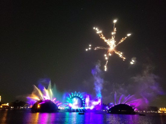 Single large fireworks explosion high up. Gateway fountains now yellow, blue and purple in order left to right.