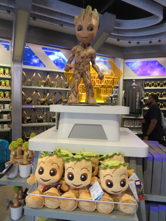 Baby Groot statue stands above an island display of stuffed Groots and potted Groots. The back of the shop also sells Loki helmets.