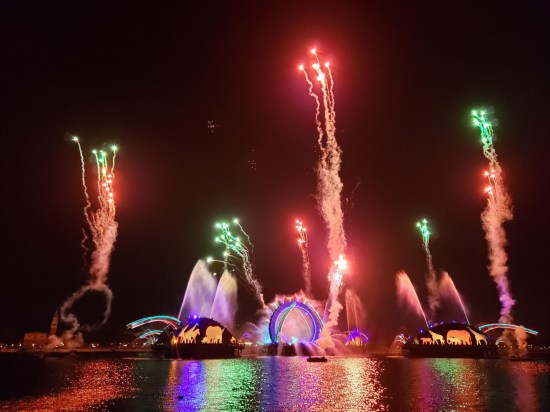 Wide shot of green and red fireworks shooting really high while yellow African animal silhouettes migrate across the black screens.