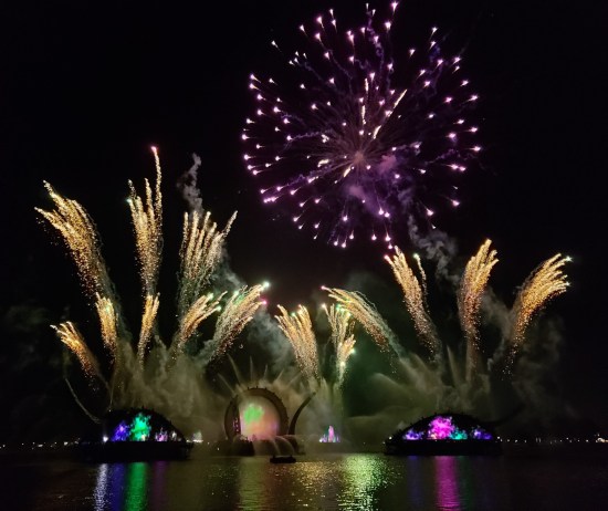 14 groups of white firework streams arcing upward, one purple explosion dissipating above them.