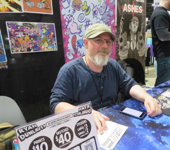 Ryan Dunlavey at his table, lots of art.