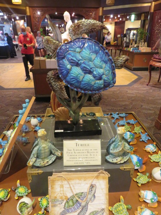 Swimming turtle statue standing in the center of a gift shop center display filled with stuffed turtles