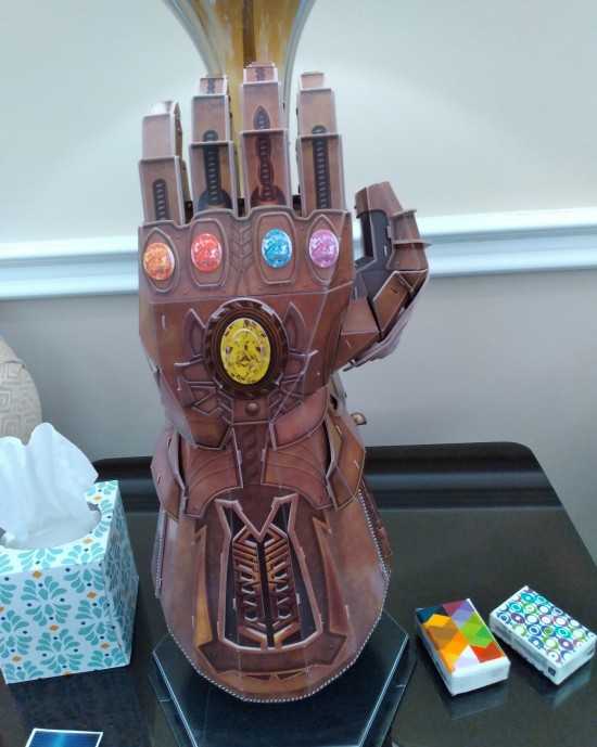 Replica Infinity Gauntlet on an end table in a mortuary next to packs of Kleenex.