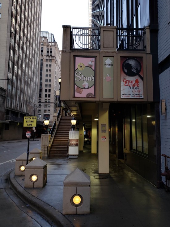 Outdoor concrete stairs leading up to a donut shop. A sign points to an escape room on the fourth floor.