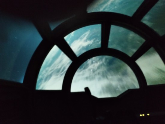 Blurry space view of an Earth-like planet from within the Millennium Falcon cockpit.