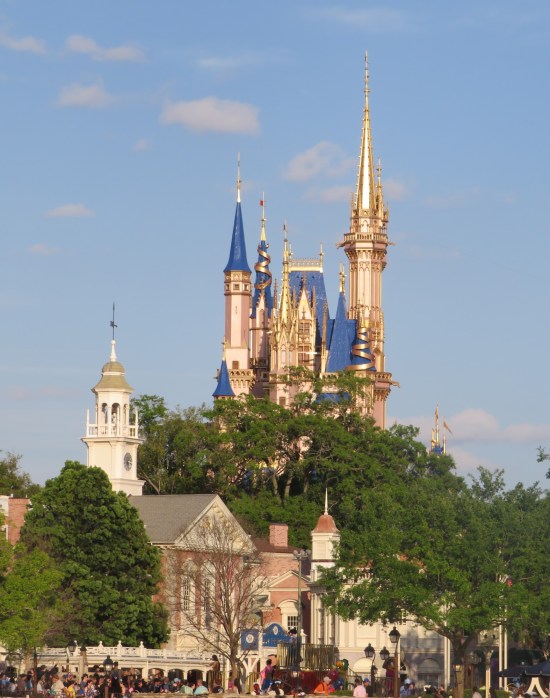 West side of Cinderella Castle with old-timey buildings blocking the view of its lower stories.