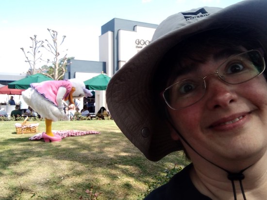 Anne taking another shadowy selfie with a goofier expression. In the distance, Daisy is hunched over her picnic blanket with the basket behind her.