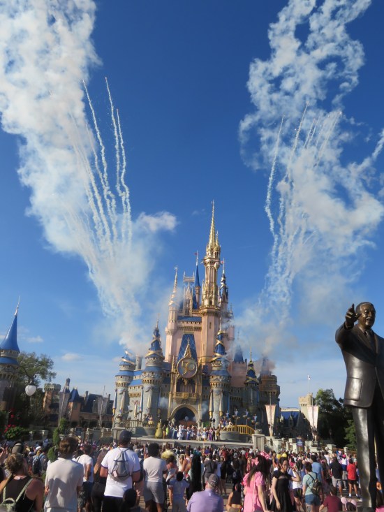 Wider shot of the castle with lots of smoke trails drifting skyward from fireworks whose sparks have since extinguished.