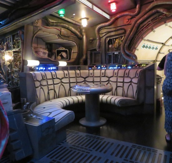 Grungy spaceship circular diner booth with round chess table. Caged red, yellow and green lights on the ceiling.