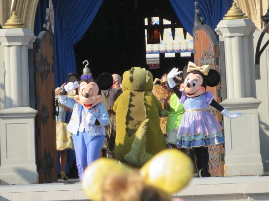 Cast exits through wooden doors mid-stage. Mickey and Minnie are last in line, waiving to the audience. Between them and facing away is Louis the crocodile from "The Princess and the Frog".