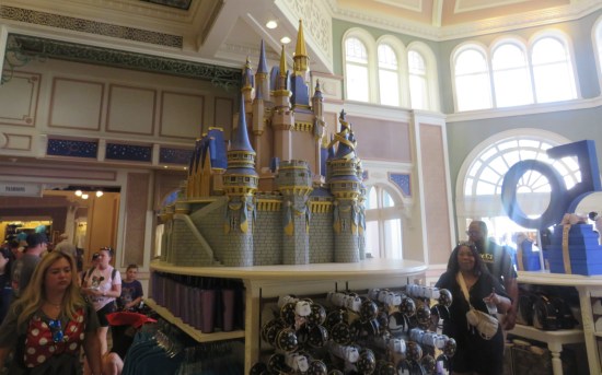 Scale model of Cinderella Castle inside a gift shop, atop a souvenir display. The gift shop walls and windows are similarly themed.