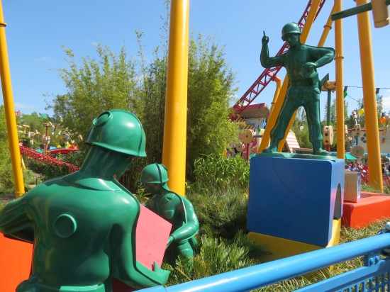 In the grass between rides, statues of green Army toys heft building blocks down a line.