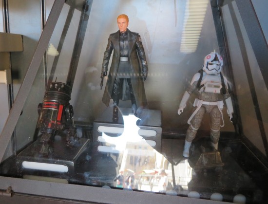 Three action figures in a glass case: General Hux, an R5 Astromech, and a Hoth AT-AT Driver..