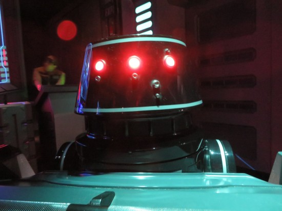 Black droid with red lights sitting at the front of our ride car.