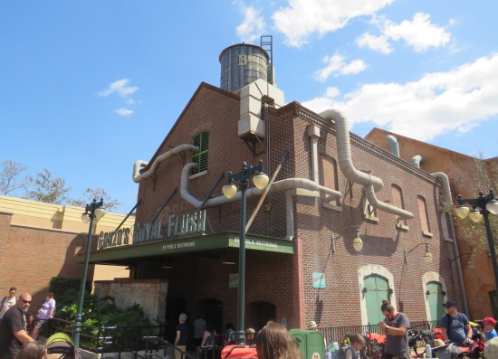 Public restrooms in a brick building with green roof and sign: "Gonzo's Royal Flush".
